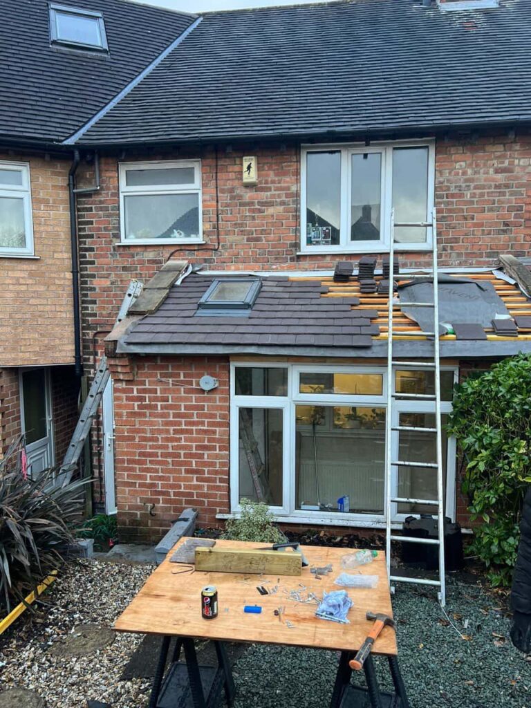 This is a photo of a roof extension that is having new roof tiles installed. This is a photo taken from the roof ridge looking down a tiled pitched roof on to a flat roof. Works carried out by Linton Roofing Repairs