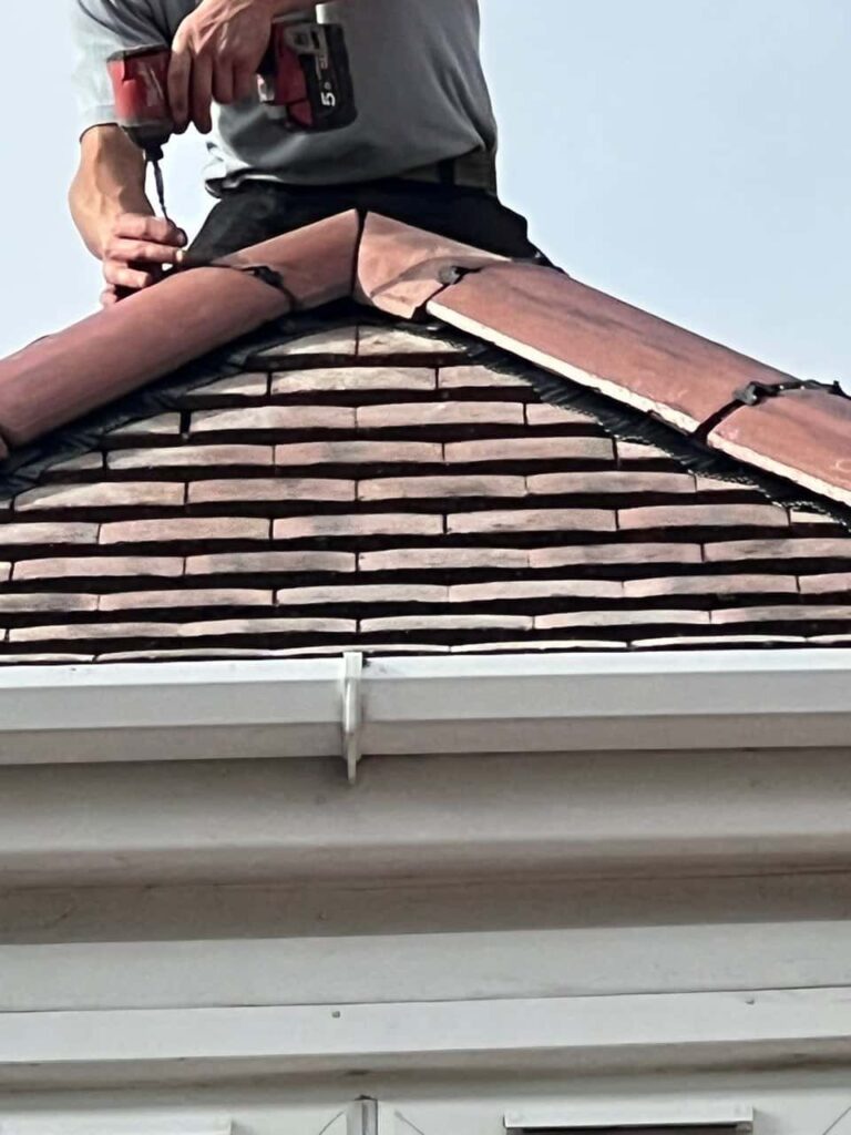 This is a photo of one of the operatives of Linton Roofing Repairs installing new ridge tiles