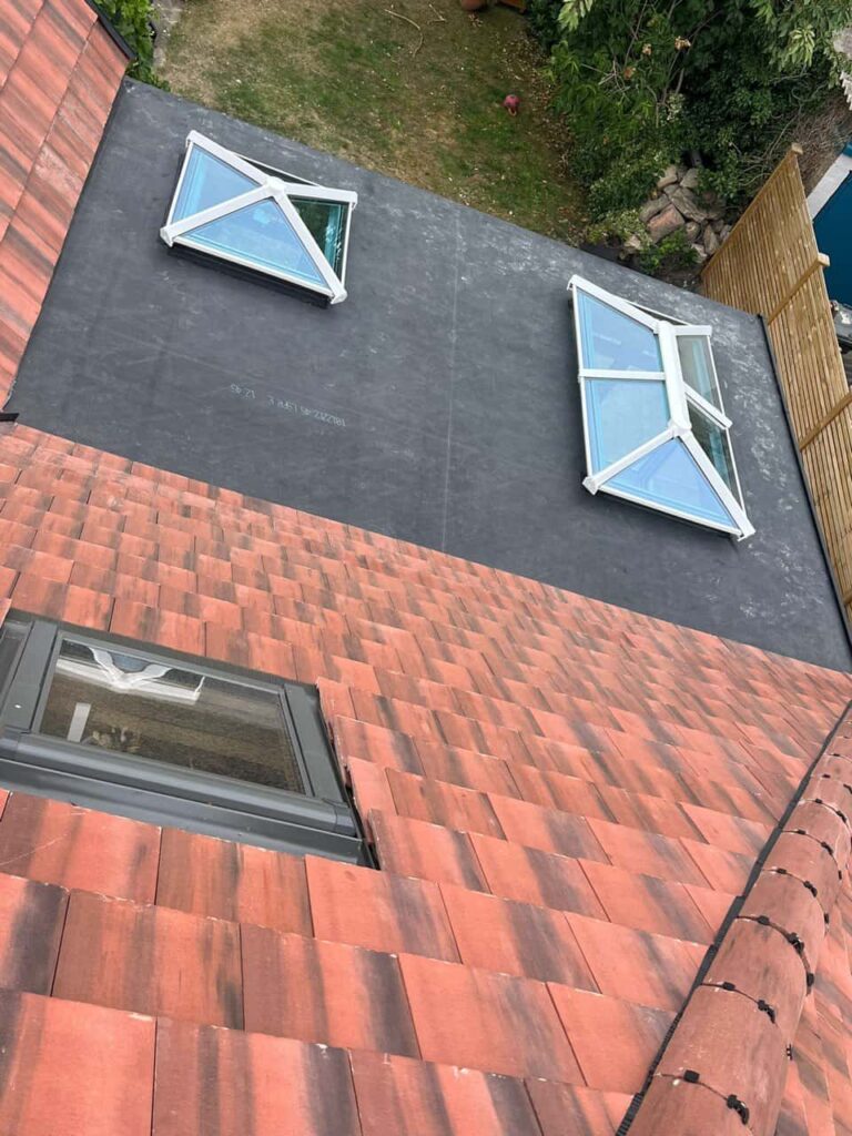 This is a photo taken from the roof ridge looking down a tiled pitched roof on to a flat roof. Works carried out by Linton Roofing Repairs